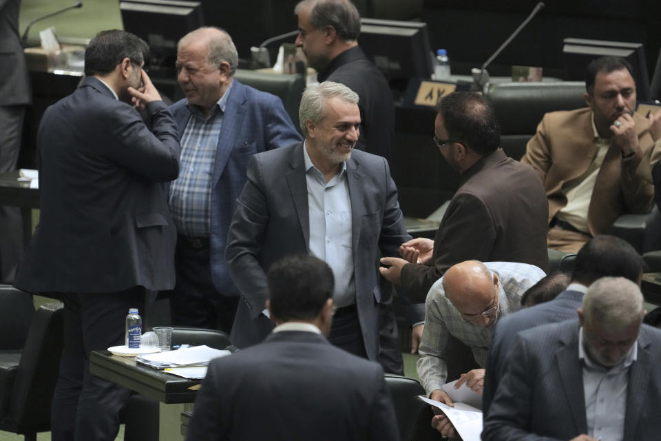 Iranian Industries Minister Reza Fatemi Amin, center, listens to an unidentified lawmaker during an open session of parliament for his impeachment, in Tehran, Iran, Sunday, April 30, 2023. Iran's parliament voted Sunday to fire Fatemi Amin over alleged mismanagement amid widespread dissatisfaction with the government. (AP Photo/Vahid Salemi)