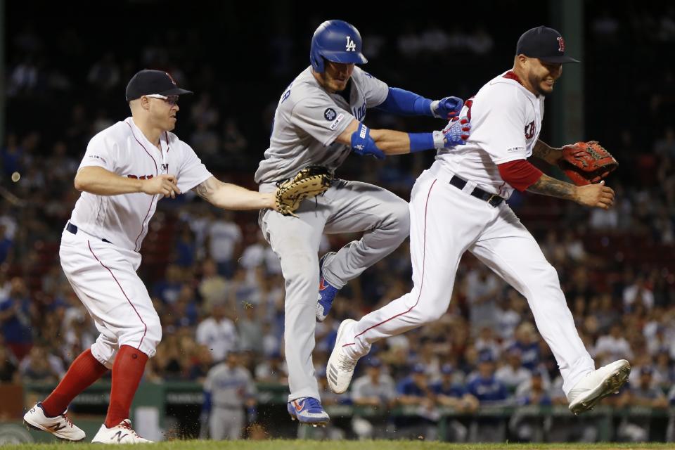 Boston Red Sox's Hector Velazquez, right, interferes with the play at first base by Brock Holt, left, allowing Los Angeles Dodgers' Cody Bellinger, center, to reach during the 12th inning of a baseball game in Boston, Monday, July 15, 2019. (AP Photo/Michael Dwyer)