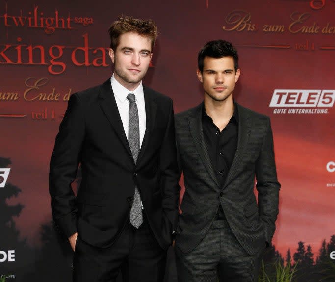 Robert Pattinson and Taylor Lautner stand together at an event