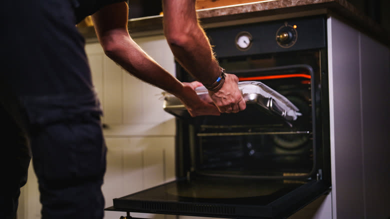 Man placing pan in oven 