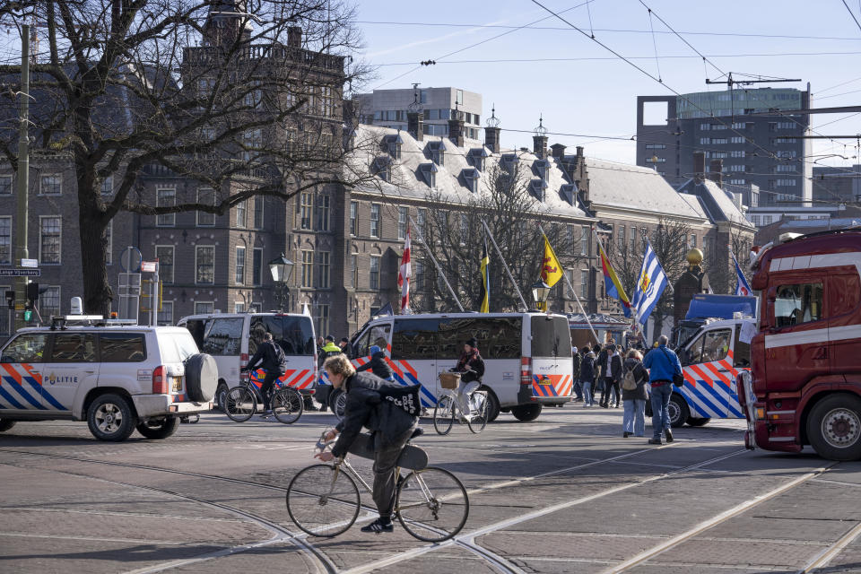 Bicycles pass police cars as some 20 trucs blocked one entrance to the government buildings, rear, in The Hague, Netherlands, Saturday, Feb. 12, 2022, to protest against COVID-19 restrictions. The events are in part inspired by protesters in Canada. (AP Photo/Peter Dejong)