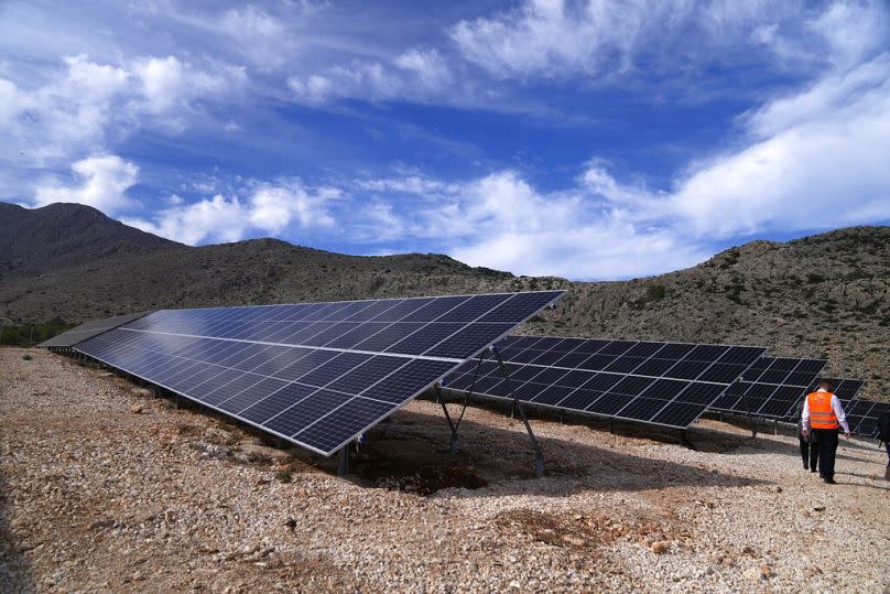 A man walks next to solar panels at a photovoltaic park at the Aegean island of Chalki, November 2021