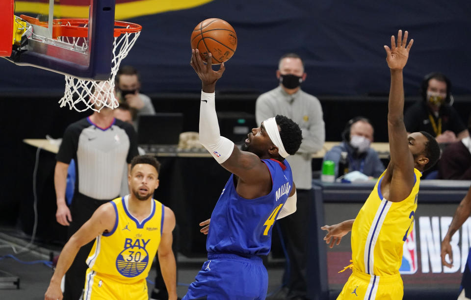 Denver Nuggets forward Paul Millsap, center, drives to the rim as Golden State Warriors guard Stephen Curry, left, and forward Andrew Wiggins defend in the first half of an NBA basketball game Thursday, Jan. 14, 2021, in Denver. (AP Photo/David Zalubowski)