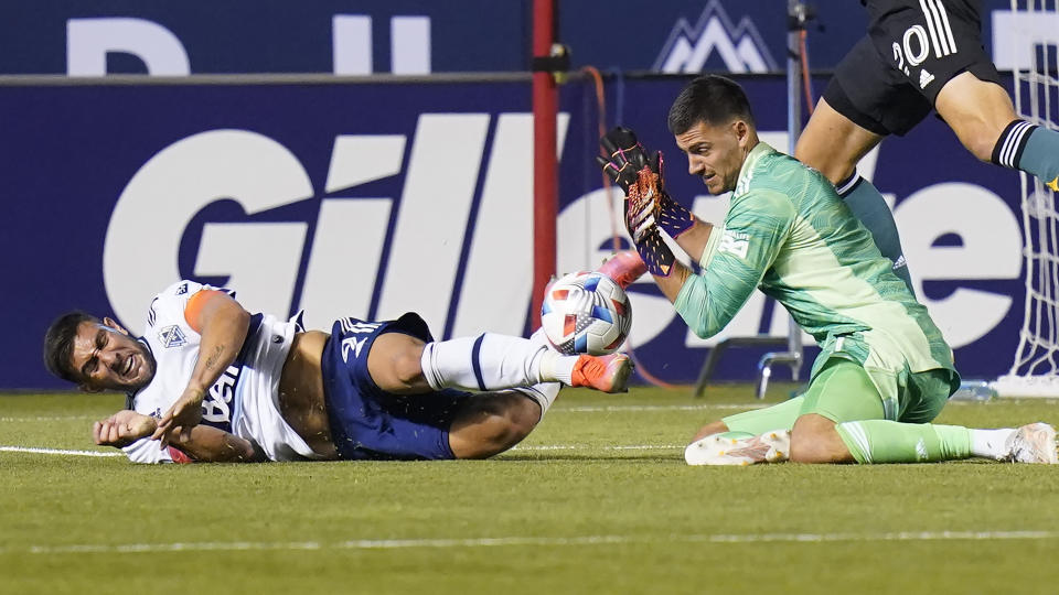 Los Angeles Galaxy goalkeeper Jonathan Bond, right, makes a save against Vancouver Whitecaps forward Lucas Cavallini, right, in the second half during an MLS soccer match Wednesday, June 23, 2021, in Sandy, Utah. (AP Photo/Rick Bowmer)