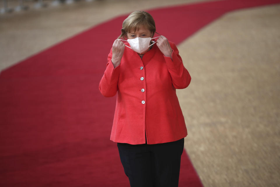 German Chancellor Angela Merkel prepares to remove her protective mask to make a statement as she arrives for an EU summit at the European Council building in Brussels, Friday, July 17, 2020. Leaders from 27 European Union nations meet face-to-face on Friday for the first time since February, despite the dangers of the coronavirus pandemic, to assess an overall budget and recovery package spread over seven years estimated at some 1.75 trillion to 1.85 trillion euros. (AP Photo/Francisco Seco, Pool)