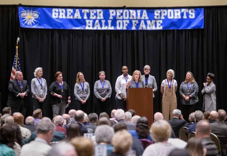 Surrounded by her former players, coach Mary Kay Hungate speaks about her 1980-81Richwoods girls basketball team during the team's induction ceremony Saturday, March 23, 2024 for the Greater Peoria Sports Hall of Fame at the Peoria Civic Center.