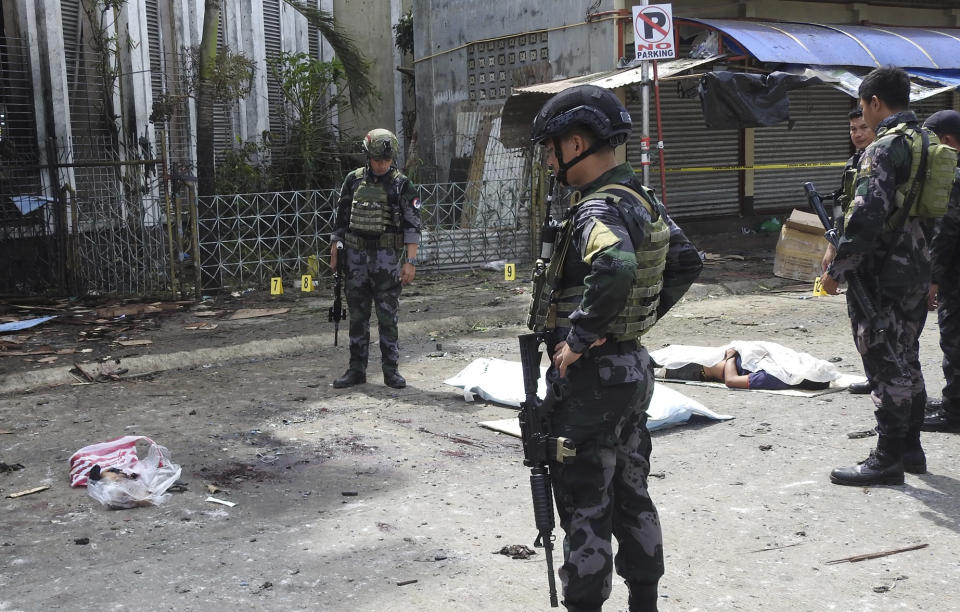 Soldiers examine the site after two bombs exploded outside a Roman Catholic cathedral in Jolo, the capital of Sulu province in southern Philippines, Sunday, Jan. 27, 2019. Two bombs minutes apart tore through a Roman Catholic cathedral on a southern Philippine island where Muslim militants are active, killing at least 20 people and wounding more than 80 others during a Sunday Mass, officials said. (AP Photo/Nickee Butlangan)