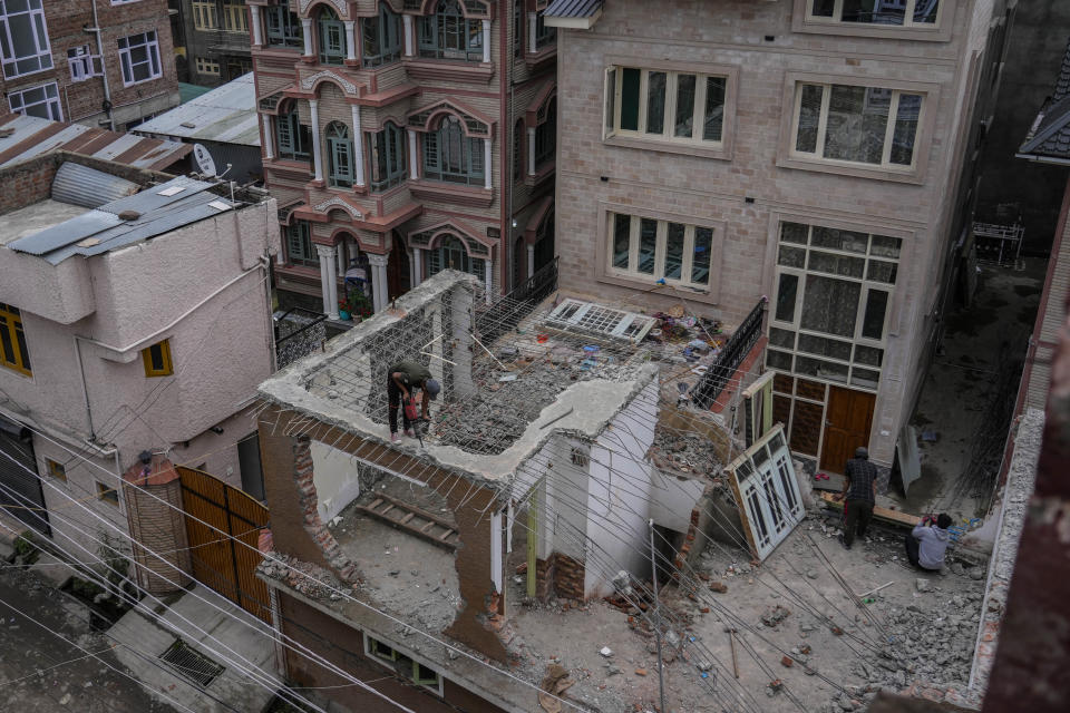 A daily wage laborer works to bring down part of a residential house on May Day in Srinagar, Indian controlled Kashmir, Monday, May 1, 2023. (AP Photo/Mukhtar Khan)