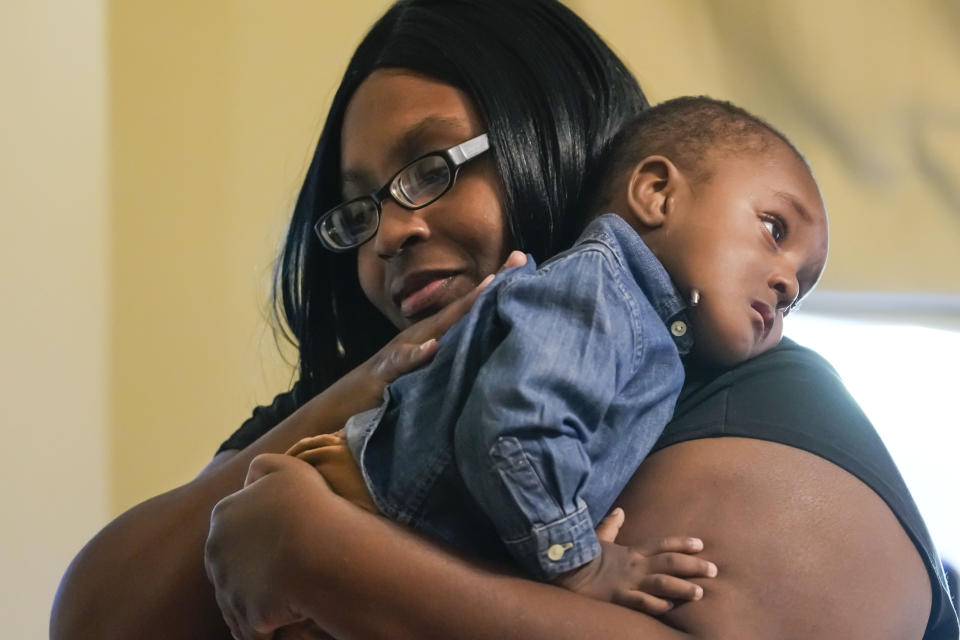 Crystal Jack holds her son Elijah Jack, 1, at her home in New Roads, La., Thursday, Nov. 30, 2023. Tulane science and engineering students are making the second batch of mobility chairs for toddlers, that will eventually go to pediatric patients at Children's Hospital. Wheelchairs are expensive, and insurance won't cover the cost for children unless the child proves they can operate it independently. (AP Photo/Gerald Herbert)