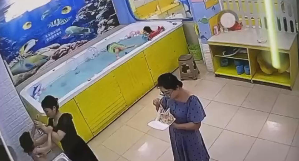 A woman eating and another changing the clothes of a child fail to notice the drowning tragedy of a little girl in China.