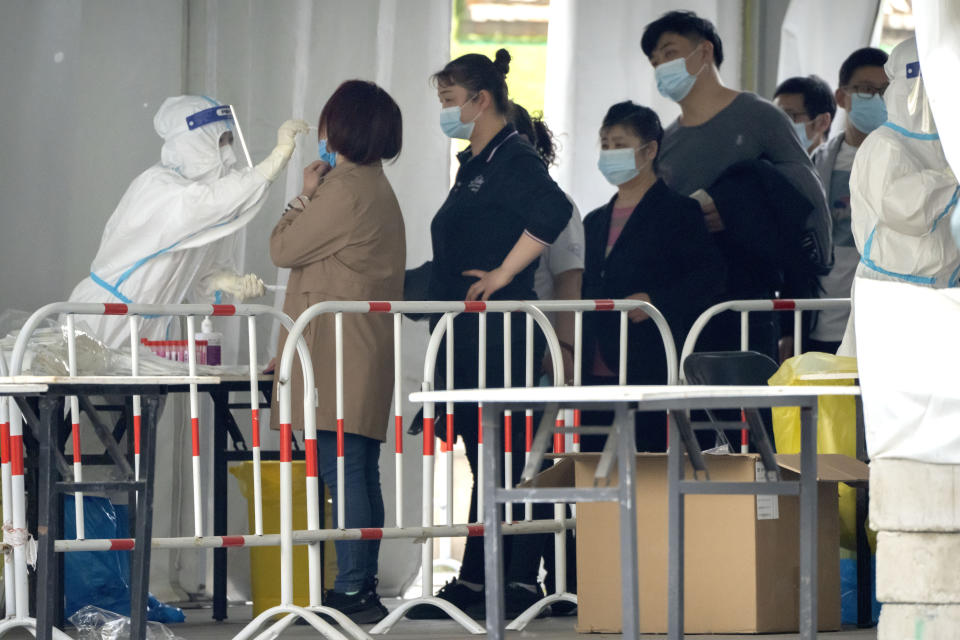 A worker in a protective takes a swab for a COVID-19 test at a coronavirus testing facility in Beijing, Saturday, April 23, 2022. Beijing is on alert after 10 middle school students tested positive for COVID-19 on Friday, in what city officials said was an initial round of testing. (AP Photo/Mark Schiefelbein)