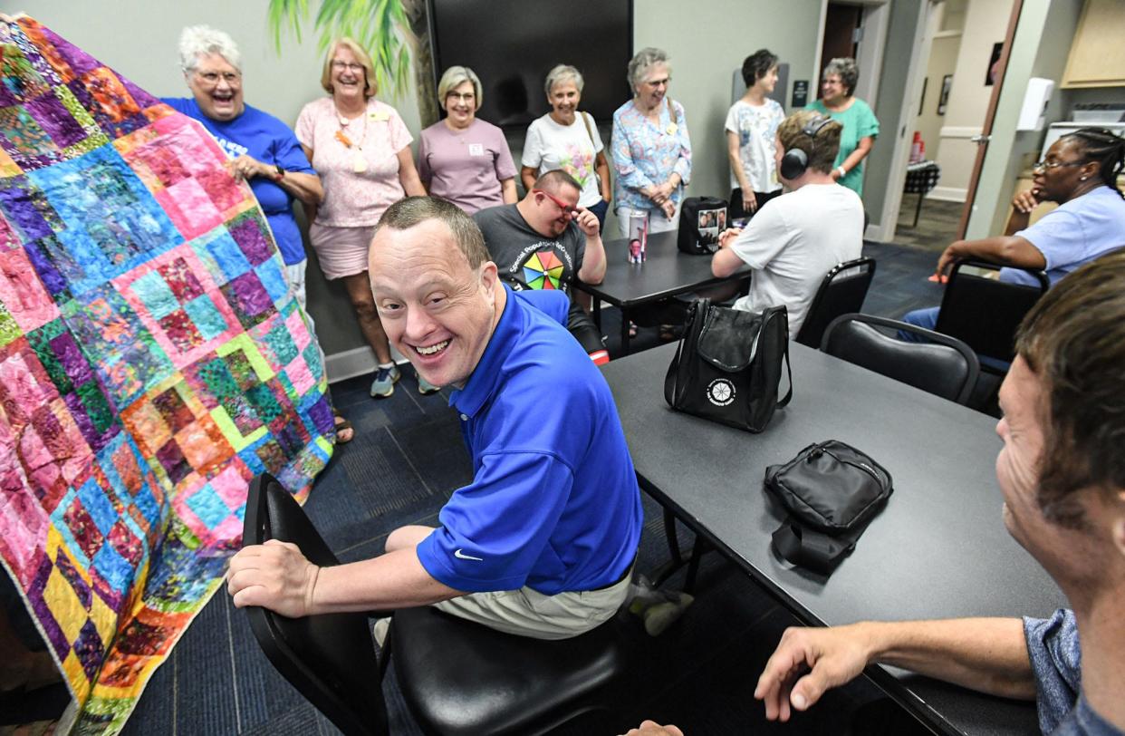 Brad Hammond, middle, smiles as Kim Price and the Quilts of Valor Foundation made a special quilt for the Rainbow Gang day care in Anderson, S.C., Monday, August 12, 2024. The quilt group, with three rooms in the same hallway of the former McCants Middle School building run by Anderson County, holds recreational activities for Anderson County Special Population.