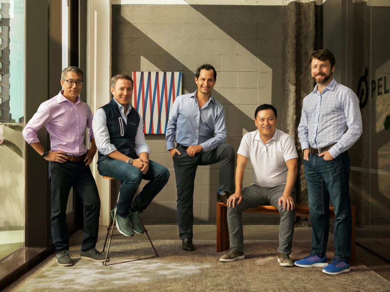 Peloton's five male cofounders sit and stand in glass-walled room