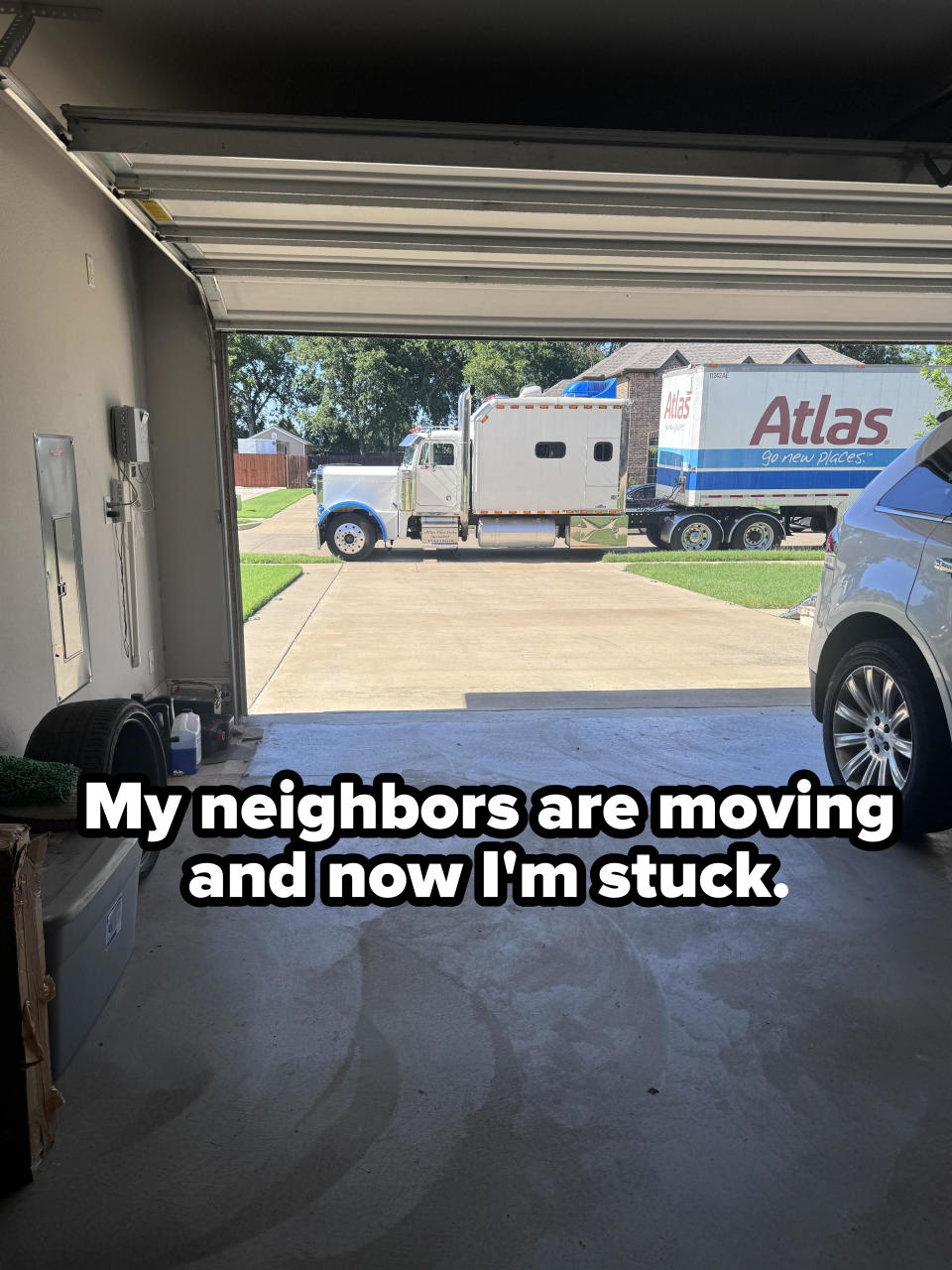 Open garage showing a moving truck labeled "Atlas" and a parked SUV. Nearby items include bins and household tools. No people are present