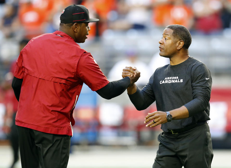 Arizona Cardinals quarterback coach Byron Leftwich, left, greets head coach Steve WIlks prior to an NFL football game against the Denver Broncos, Thursday, Oct. 18, 2018, in Glendale, Ariz. The Cardinals announced Friday, Oct. 19, 2018, that offensive coordinator Mike McCoy has been relieved of his duties and that Byron Leftwich will assume his position. (AP Photo/Ralph Freso)