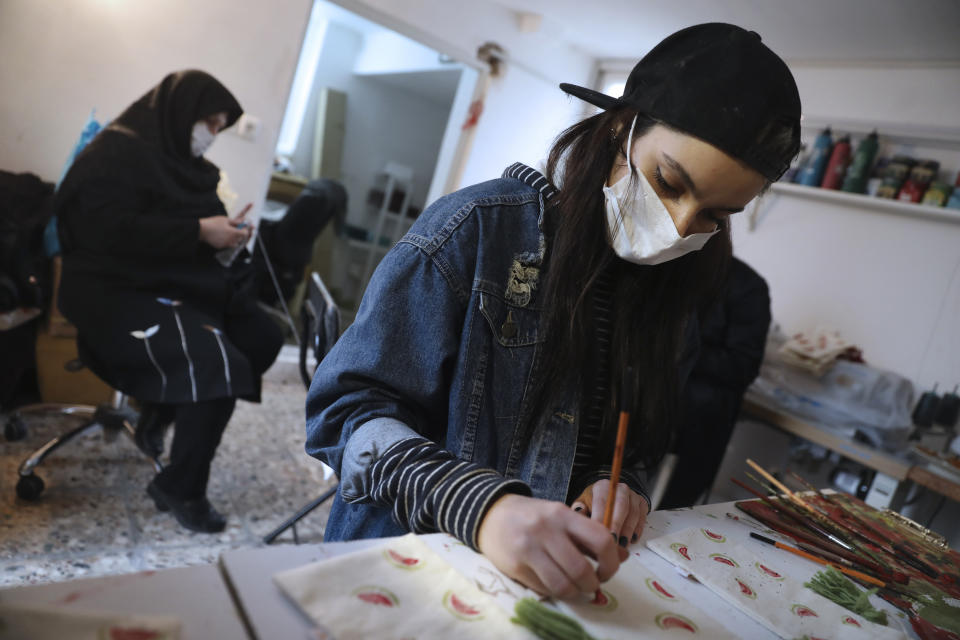 Bahareh Eskandarkhan paints on a cloth bag at a workshop of Bavar charity in Tehran, Iran, Monday, Nov. 23, 2020. As the coronavirus pandemic ravages Iran, a women’s group hopes to empower its members by helping them make and sell face masks. (AP Photo/Vahid Salemi)