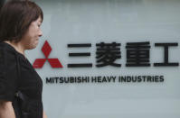 A woman walks past the company sign of the Mitsubishi Heavy Industries in Tokyo, Tuesday, July 23, 2019. Colonial-era Korean laborers have formally registered their request with a South Korean court to get its approval for the sale of local assets of their former Japanese employer. (AP Photo/Koji Sasahara)