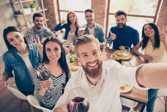 A group of friends around a table taking a selfie.
