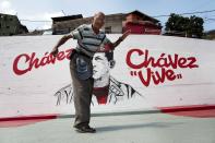 Un hombre se detiene a medio paso cuando se da cuenta que ha entrado en el lente del fotógrafo que tomaba una imagen frente a un mural del fallecido presidente de Venezuela, Hugo Chávez, en Caracas, Venezuela el martes 4 de marzo de 2014. Aunque murió hace un año, el rostro y la voz de Chávez aparecen por doquier. Su voz cantando el himno nacional suena en la radio estatal todas las mañanas y la Guardia Nacional ha aumentado el volumen de su voz cuando recitaba poesía para diseminar a los manifestantes que les arrojan piedras en las calles. Con motivo del aniversario de Chávez, el presidente Nicolás Maduro ha decretado diez días de conmemoración y que, en total, suman tres más de los días de luto oficial que fueron decretados una semana después de su deceso. Chávez murió a los 58 años el 5 de marzo de 2013. (AP Photo / Rodrigo Abd)