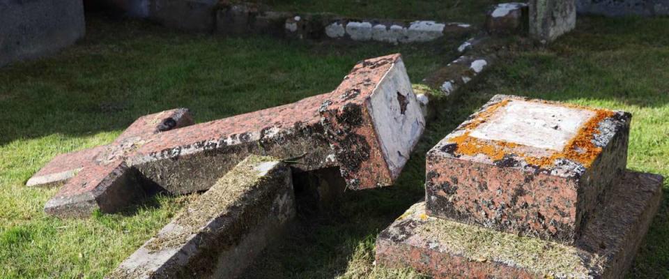 Broken cross in a cemetery at a grave in Scotland