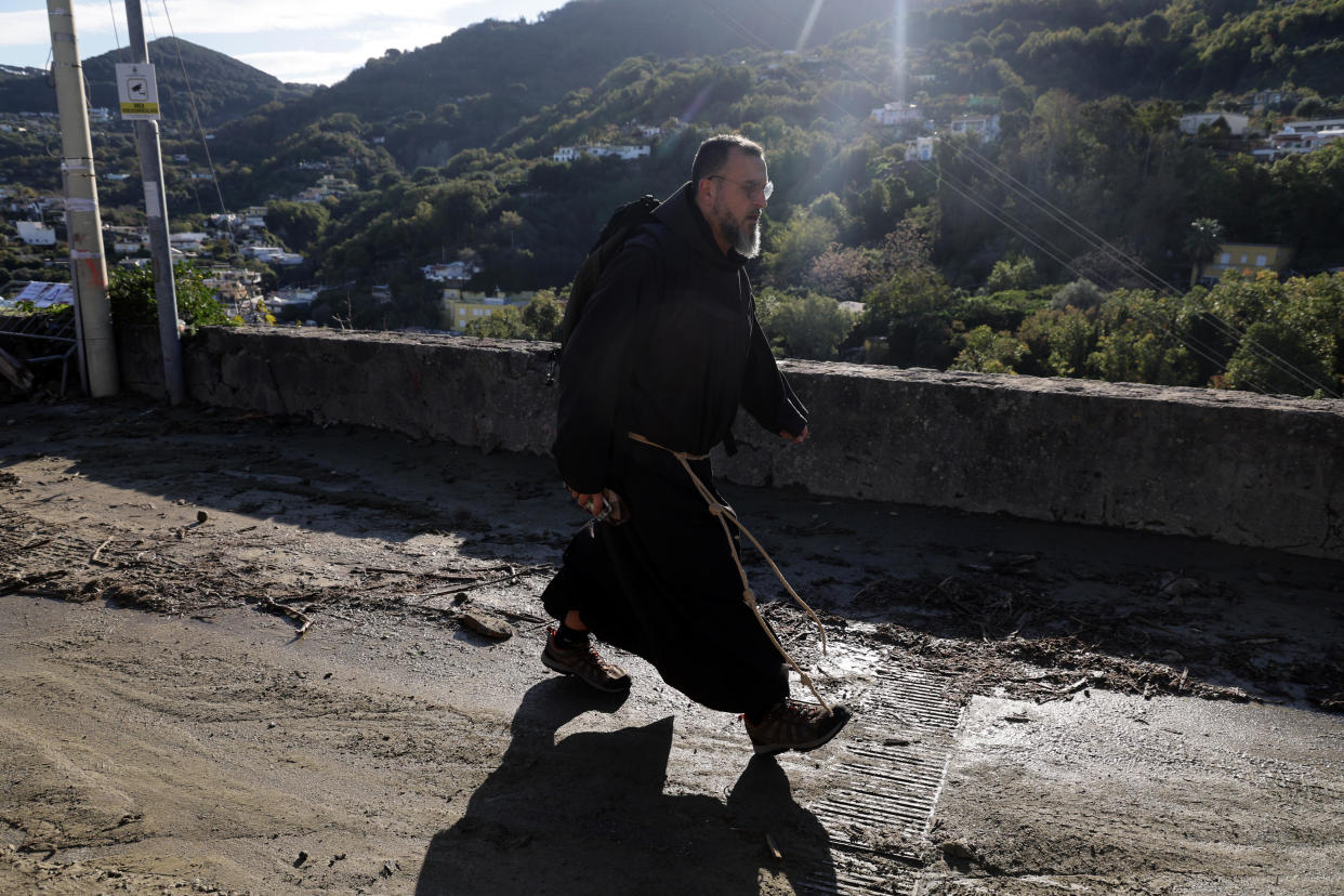 A friar walks down a mud covered road after heavy rainfall triggered landslides that collapsed buildings and left as many as 12 people missing, in Casamicciola, on the southern Italian island of Ischia, Sunday, Nov. 27, 2022. Authorities said that the landslide that early Saturday destroyed buildings and swept parked cars into the sea left one person dead and 12 missing. (Alessandro Garofalo/LaPresse via AP)