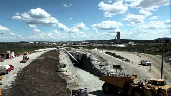 Mining operation with trucks, equipment, and cuts all shown in an arid landscape.