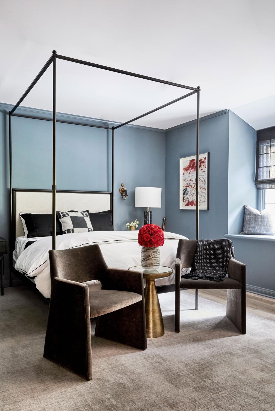 In the guest room, which Nicolas describes as “a little moody,” a lofty RH bed is a focal point alongside velvet CB2 chairs and a Cy Twombly artwork.