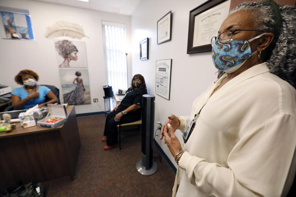 Clinician and social worker Lisa Williams, right, speaks in front of, Chinnika Crisler, left, and Kim Tate, center, Aug. 14, 2020, at the Community Health Care Center on the campus of Tougaloo College in Tougaloo, Miss. Williams said although the coronavirus pandemic has made a lot of the issues that patients deal with worse, they aren't anything new. “People have been struggling for a long, long time," she said. (AP Photo/Rogelio V. Solis)