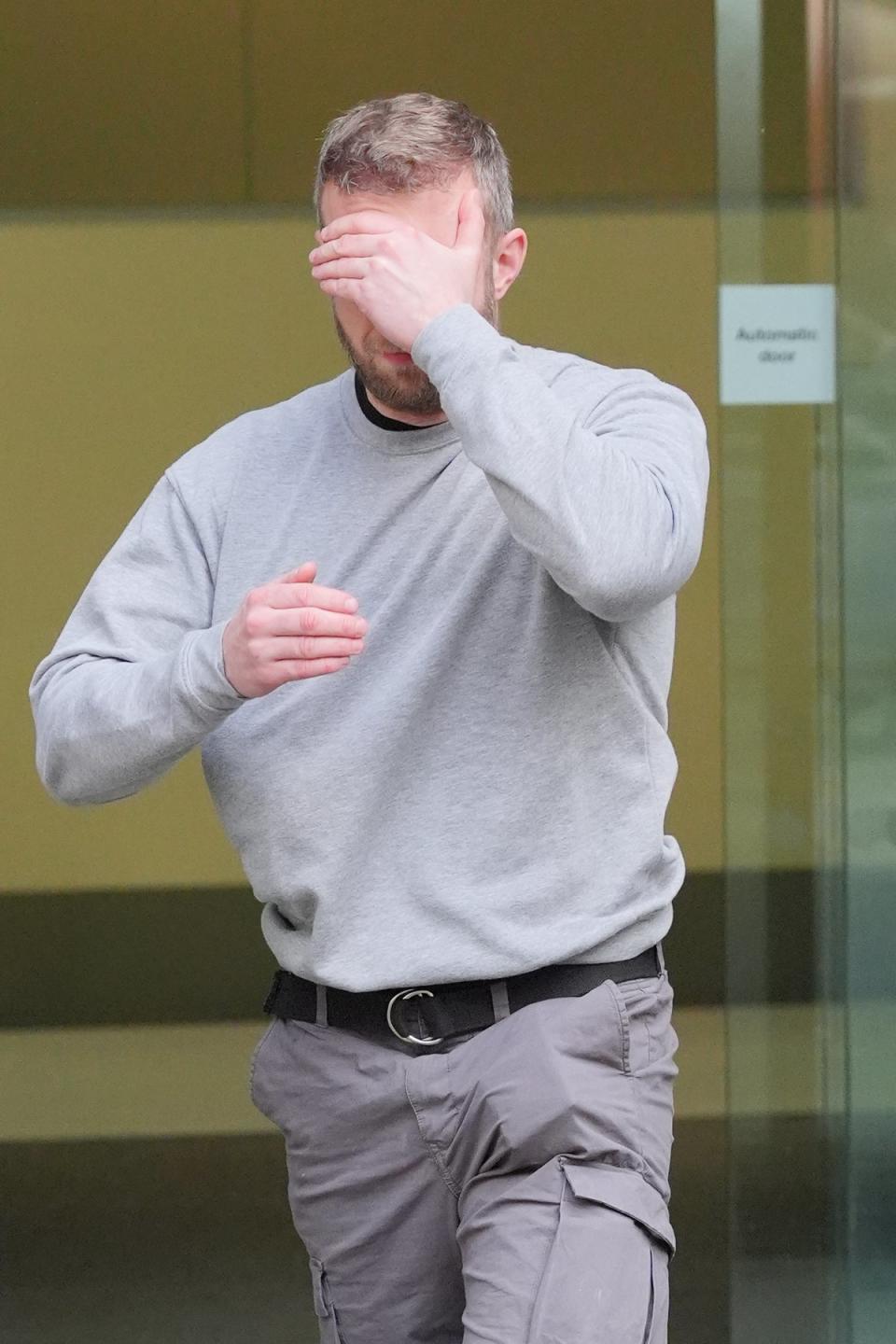 Matthew Trickett covering his face as he left Westminster Magistrates’ Court, central London, after appearing in court accused of assisting the Hong Kong intelligence service (PA)