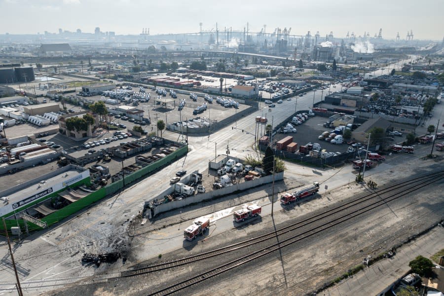 The tractor portion of a big rig, at left, is shown in an aerial view on Thursday, Feb. 15, 2024, in the Wilmington section of Los Angeles. Several Los Angeles firefighters were injured, two critically, when an explosion occurred as they responded to a truck with pressurized cylinders that were on fire early Thursday, authorities said. (AP Photo/William Liang)