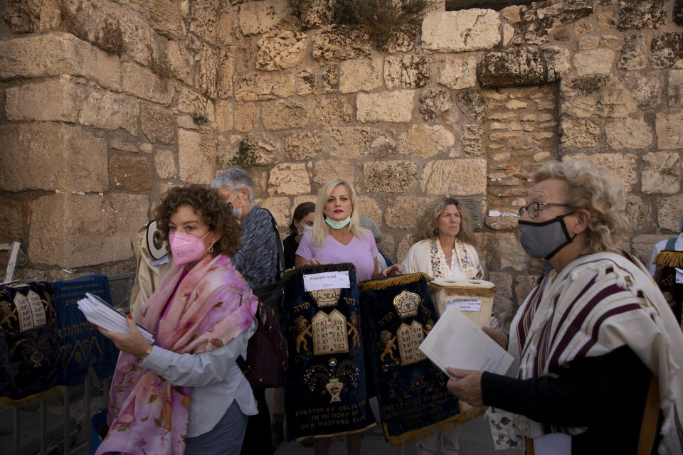 Members of the Women of the Wall display the Torah scroll covers as they gather for the Rosh Hodesh, or new month prayer in the women's section at the Western Wall, the holiest site where Jews can pray, in the Old City of Jerusalem, Friday, Nov. 5, 2021. Thousands of ultra-Orthodox Jews gathered at the site to protest against the Jewish women's group that holds monthly prayers there in a long-running campaign for gender equality at the site. (AP Photo/Maya Alleruzzo)