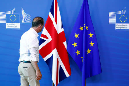 FILE PHOTO - An official inspects a Union Jack flag next to the European Union flag, ahead of a meeting between Britain's Secretary of State for Exiting the European Union, Dominic Raab, and European Union's chief Brexit negotiator, Michel Barnier, at the EU Commission headquarters in Brussels, Belgium July 19, 2018. REUTERS/Francois Lenoir