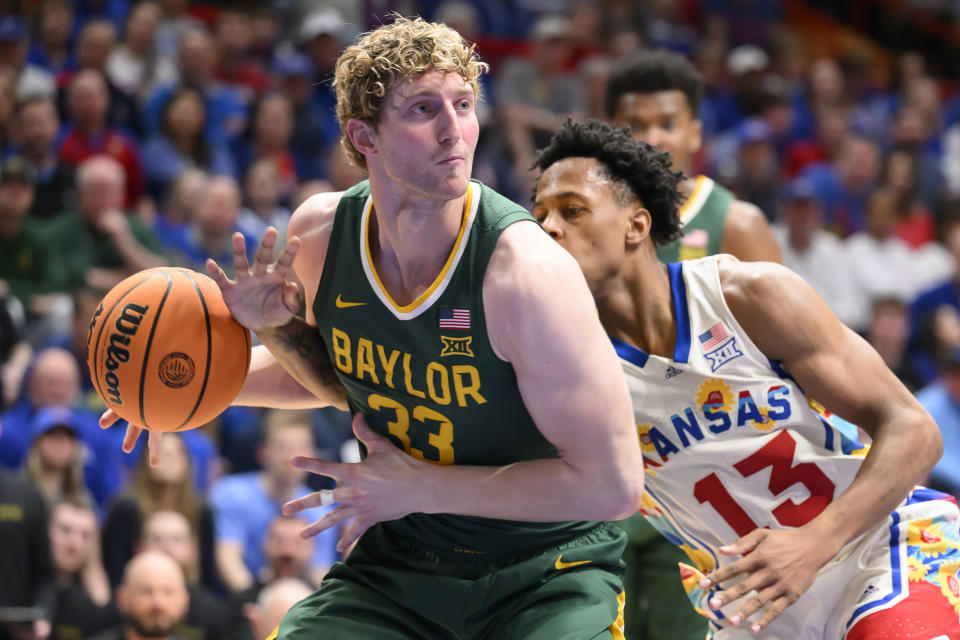 Kansas guard Elmarko Jackson (13) tries to knock the ball away from Baylor forward Caleb Lohner (33) during the second half of an NCAA college basketball game in Lawrence, Kan., Saturday, Feb. 10, 2024. (AP Photo/Reed Hoffmann)