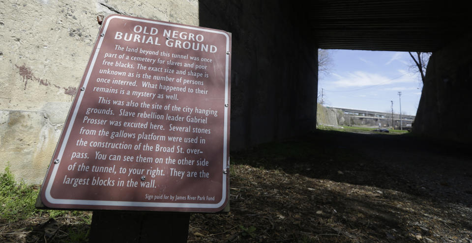 A historical marker designating the Old Negro Burial Ground is displayed in Richmond, Va., Monday, March 31, 2014. A proposal to build a minor league baseball stadium in Shockoe Bottom, the city’s oldest neighborhood and the center of the once-thriving slave trade, has drawn criticism from some who believe the area is sacred ground and shouldn’t be bulldozed for a ballpark. The city says it will recover and display artifacts related to the slave trade. (AP Photo/Steve Helber)