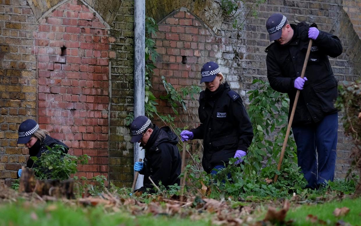 Police officers search an area in Edmonton, north London, where a man was murdered