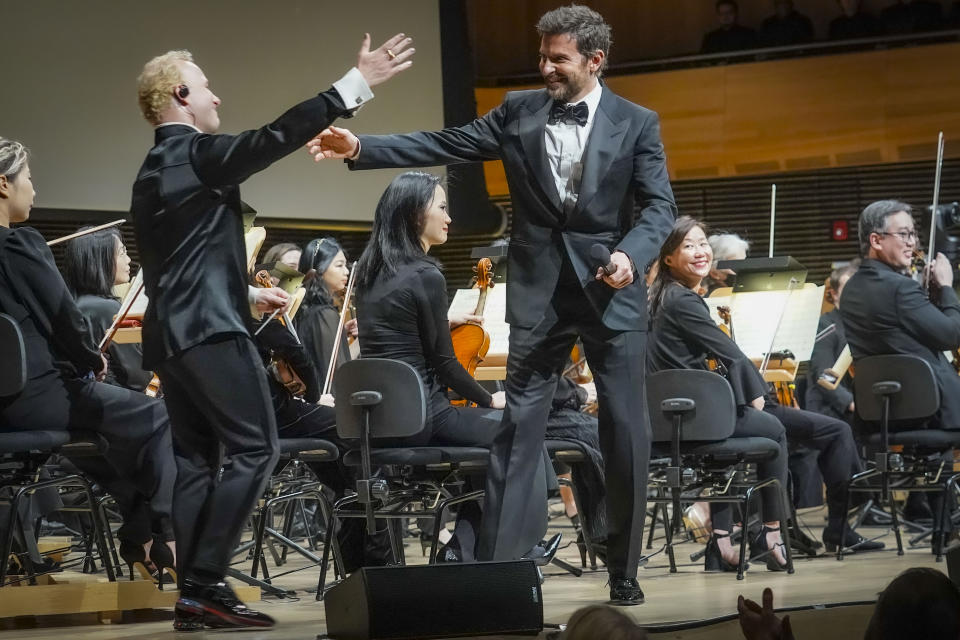 The Metropolitan Opera new music director Yannick Nézet-Séguin, left, greet actor and director Bradley Cooper, center, as he comes on stage to conduct the New York Philharmonic, Wednesday, Feb. 14, 2024, in New York. (AP Photo/Bebeto Matthews)