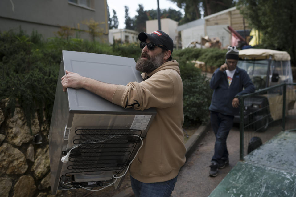 Dan Ittah, 39, resident from Kibbutz Nahal Oz, carries a small refrigerator as he works in Kibbutz Mishmar HaEmek, northern Israel, Monday, Feb. 5, 2024. (AP Photo/Leo Correa)