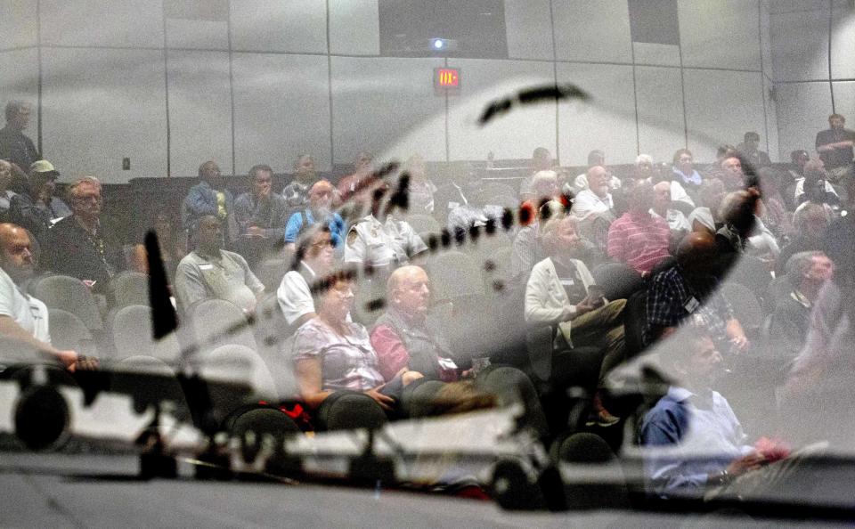 In this Friday, Sept. 20, 2013 photo, an image of a plane hangs on the wall as airport chaplains are reflected during a presentation at the International Association of Civil Aviation Chaplains' annual conference at Delta Air Lines' headquarters, in Atlanta. Airports are mini-cities with their own movie theaters, fire departments and shopping malls. Many also have chapels, which are staffed by a mix of 350 part- and full-time chaplains worldwide who are Catholic, Protestant and, to a lesser extent, Jewish, Muslim or Sikh. (AP Photo/David Goldman)