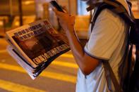 A man takes a photo of his copy of the Apple Daily newspaper after it looked set to close for good by Saturday following police raids and the arrest of executives in Hong Kong