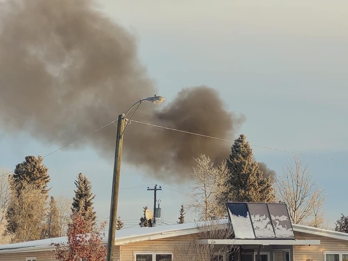 Smoke billows up behind a house in Hay River, N.W.T. An explosion Saturday morning rocked the town, with some residents reporting that the shockwave broke their windows and knocked pictures off their walls. (April Martel/Facebook - image credit)