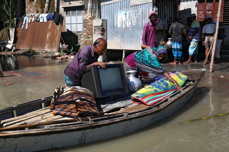 FILE PHOTO: A family moves to a safe place with their belongings after the flood situation worsened in Munshiganj district, on the outskirts of Dhaka