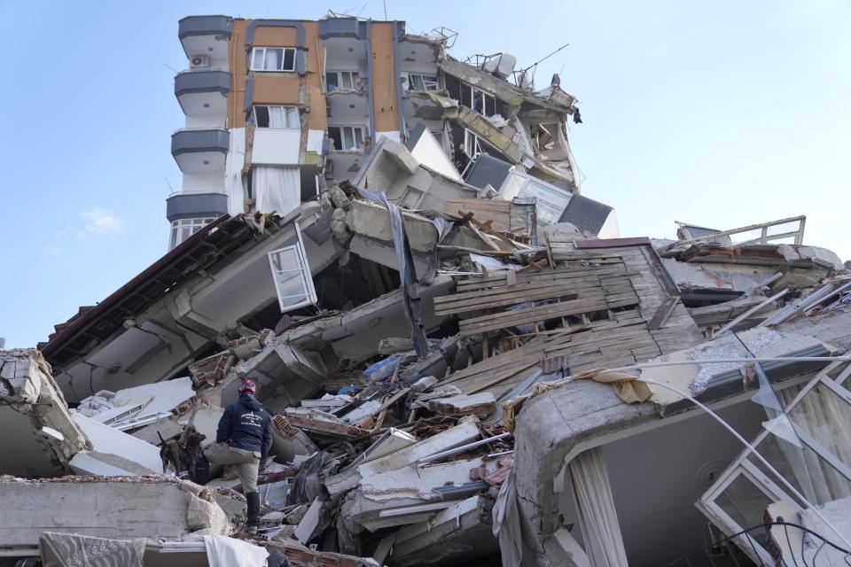 A rescuer with a sniffer dog searches in a destroyed building in Antakya, southeastern Turkey, Friday, Feb. 10, 2023. Rescuers pulled several earthquake survivors from the shattered remnants of buildings Friday, including some who lasted more than 100 hours trapped under crushed concrete after the disaster slammed Turkey and Syria. (AP Photo/Hussein Malla)