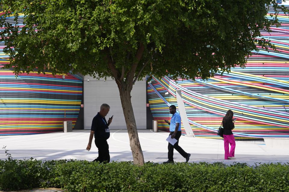 People walk though the COP28 U.N. Climate Summit, Monday, Dec. 4, 2023, in Dubai, United Arab Emirates. (AP Photo/Kamran Jebreili)