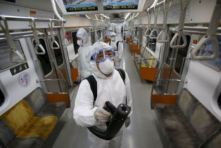 Workers in full protective gear disinfect the interior of a subway train at a Seoul Metro's railway vehicle base in Goyang, South Korea, June 9, 2015. REUTERS/Kim Hong-Ji