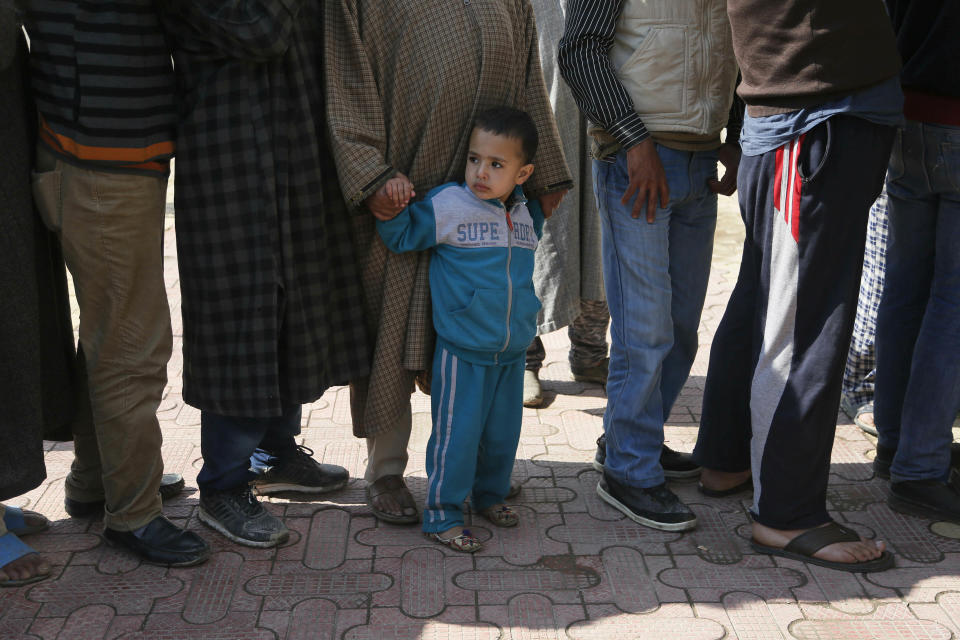 A boy stands holding the hand of a Kashmiri voter waiting in a queue to cast his vote, outside a poling station during the second phase of India's general elections on the outskirts of Srinagar, Indian controlled Kashmir, Thursday, April 18, 2019. Kashmiri separatist leaders who challenge India's sovereignty over the disputed region have called for a boycott of the vote. Most polling stations in Srinagar and Budgam areas of Kashmir looked deserted in the morning with more armed police, paramilitary soldiers and election staff present than voters. (AP Photo/Mukhtar Khan)