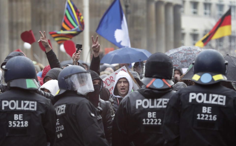 A protestor shouts as police officers block a road between the Brandenburg Gate and the Reichstag building, home of the German federal parliament, as people attend a protest rally in front of the Brandenburg Gate in Berlin, Germany, Wednesday, Nov. 18, 2020 against the coronavirus restrictions in Germany. Police in Berlin have requested thousands of reinforcements from other parts of Germany to cope with planned protests by people opposed to coronavirus restrictions. (AP Photo/Michael Sohn)