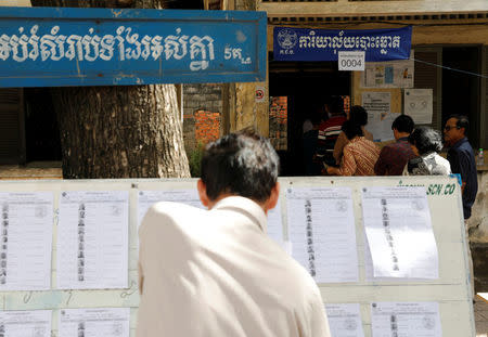 A man looks at a voter list as others line up to vote at a polling station during a general election in Phnom Penh, Cambodia July 29, 2018. REUTERS/Darren Whiteside