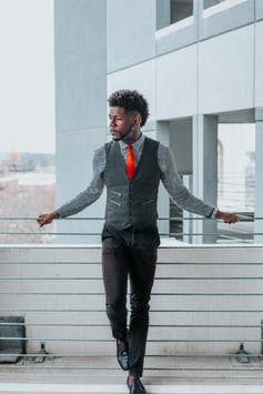 Man in a waistcoat and shirt outside an office, looking over a barrier