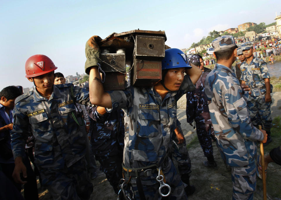 A Nepalese rescue worker carries the flight data recorder of a Sita Air airplane at the crash site near Katmandu, Nepal, early Friday, Sept. 28, 2012.  The plane carrying trekkers into the Everest region crashed just after takeoff Friday morning in Nepal's capital, killing all 19 people on board, authorities said. (AP Photo/Niranjan Shrestha)