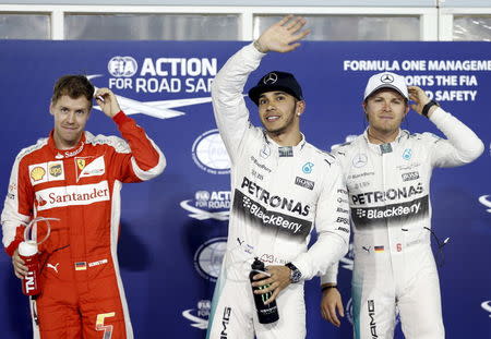 Mercedes Formula One driver Lewis Hamilton (C) of Britain celebrates taking the pole position beside Ferrari Formula One driver Sebastian Vettel (L) of Germany and Mercedes Formula One driver Nico Rosberg of Germany ahead of Bahrain's F1 Grand Prix at Bahrain International Circuit, south of Manama April 18, 2015. REUTERS/Ahmed Jadallah